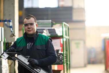 Modern bir metal üretim ve işleme fabrikasında çalışan üniformalı bir işçi masasında yeni bir makinenin parçalarını birleştiriyor. Yüksek kalite fotoğraf