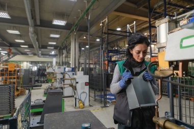 Modern bir metal fabrikasında çalışan bir kadın yeni bir makine için parça topluyor. Yüksek kalite fotoğraf