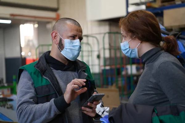 工場で生産を議論コロナウイルスから保護された顔マスクを持つ産業労働者 Covid 19パンデミック時に働く人々 高品質の写真 — ストック写真