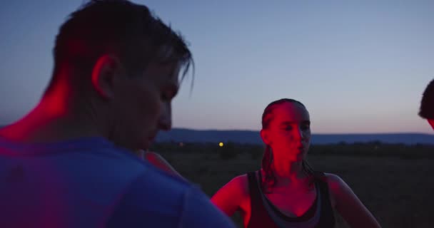 Grupo multiétnico de atleta descansando depois de correr à noite em uma estrada panorâmica — Vídeo de Stock