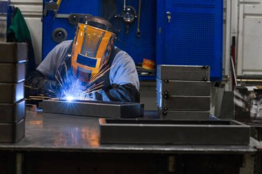 Profesyonel kaynakçı, fabrika, kıvılcım ve elektrikte metal parçalarıyla iş yapıyor. Sanayi işçisi afişi. Yüksek kalite fotoğraf