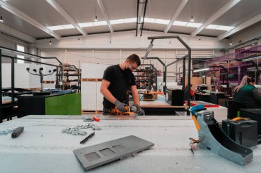 Heavy Industry Engineering Factory Interior with Industrial Worker Using Angle Grinder and Cutting a Metal Tube. Coronavirüs salgını yüzünden yüzüne maske takıyor. Yüksek kalite fotoğraf