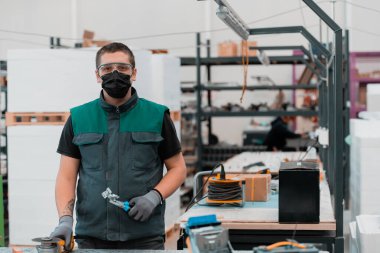 Heavy Industry Engineering Factory Interior with Industrial Worker using Angle Grinder and cut a Metal Tube. Coronavirus Pandemic yüzünden yüzüne maske takıyor. Yüksek kalite fotoğraf