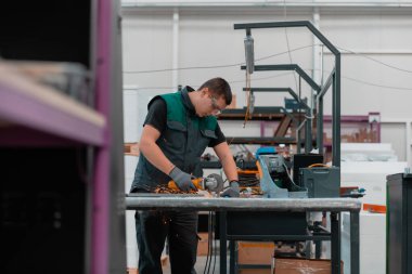 Heavy Industry Engineering Factory Interior with Industrial Worker Using Angle Grinder and Cutting a Metal Tube. Güvenlik Üniforması ve Sert Şapka Üretim Metal Yapıları Müteahhiti. Yüksek kalite