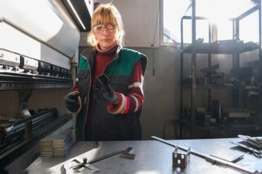 Modern bir fabrikada çalışan ve CNC makinesi için malzeme hazırlayan bir kadın. - Evet. Yüksek kalite fotoğraf