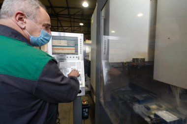Akıllı bir fabrika işçisi ya da mühendisi salgın yüzünden maske takar ve bir üretim atölyesinde makine yapar. Endüstri ve mühendislik kavramı. Yüksek kalite fotoğraf