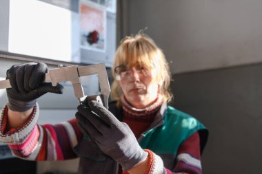 Metal üretimi ve işlemesi için modern bir fabrikada çalışan bir kadın CNC makinelerinin işlenmesinde kullanılan materyalleri hazırlıyor ve ölçüyor. Yüksek kalite fotoğraf