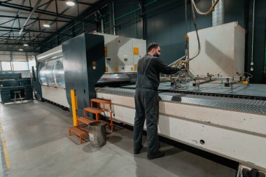 Salgın yüzünden maske takan ve üretim atölyesinde makine yapan zeki bir fabrika işçisi ya da mühendis. Endüstri ve mühendislik kavramı. Yüksek kalite fotoğraf