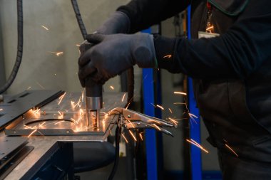 Modern metal üretim ve işleme endüstrisinde çalışan bir kadın ürünü kaynak yaparak CNC makinesine hazırlıyor. Yüksek kalite fotoğraf