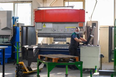 Akıllı bir fabrika işçisi ya da mühendisi salgın yüzünden maske takar ve bir üretim atölyesinde makine yapar. Endüstri ve mühendislik kavramı. Yüksek kalite fotoğraf