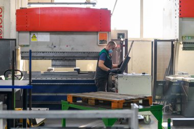 Akıllı bir fabrika işçisi ya da mühendisi salgın yüzünden maske takar ve bir üretim atölyesinde makine yapar. Endüstri ve mühendislik kavramı. Yüksek kalite fotoğraf