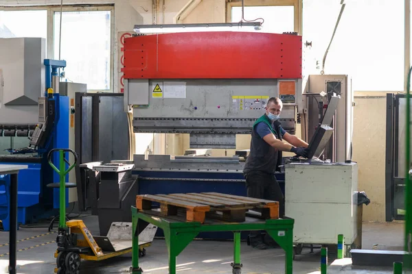 Akıllı bir fabrika işçisi ya da mühendisi salgın yüzünden maske takar ve bir üretim atölyesinde makine yapar. Endüstri ve mühendislik kavramı. Yüksek kalite fotoğraf