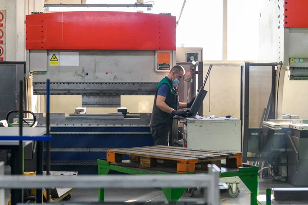 Akıllı bir fabrika işçisi ya da mühendisi salgın yüzünden maske takar ve bir üretim atölyesinde makine yapar. Endüstri ve mühendislik kavramı. Yüksek kalite fotoğraf