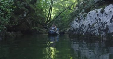 Kano yavaş çekimde kürek çekiyor. Kanocu kadın ve erkek arkadaşlarıyla güzel bir arazide kayak yapıyor. Kayakçılar gölde bir kanoyla spor yapıyorlar. Yaz boyunca su sporları. Yüksek kalite 4k görüntü