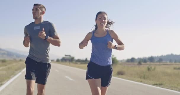 Seguimiento de la toma de cámara lenta de la pareja deportiva corriendo al aire libre en la mañana, la experiencia de trail running en la naturaleza. concepto de estilo de vida saludable. — Vídeos de Stock