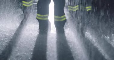 Profesyonel itfaiyecilerden oluşan bir ekip yağmurda miğferler ve yangın kıyafetleriyle bekliyor. Yüksek kaliteli görüntüler