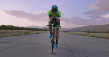 Profesyonel bir yarış bisikletine binen triatlon sporcusunun gece bisikleti eğitimi. Akşamları virajlı bir yolda sağlıklı ve yoğun bir egzersiz. Yavaş çekim izleme çekimi. 