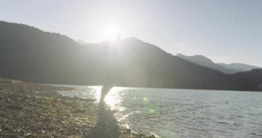 Dalgıç kıyafetli profesyonel triatlon sporcusu demir adam yarışması için yüzme antrenmanına bir gölün su sıçratan sularında koşup zıplayarak başlıyor. Yavaş çekim izleme çekimi. 