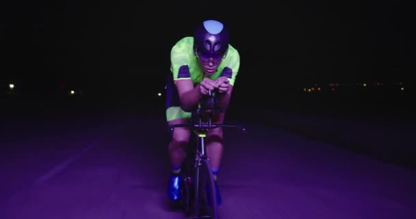 プロのレーシングバイクに乗ってトライアスロン選手の夜の自転車トレーニング 夕方には曲がりくねった田舎道で健康的な強烈なワークアウト スローモーショントラッキングショット — ストック動画