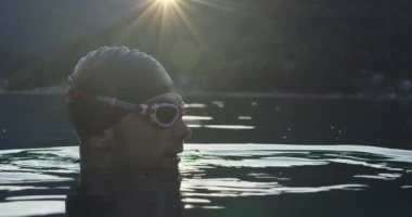 Triatlon sporcusu sabahları yoğun antrenman sırasında mola veriyor. Profesyonel bir dalış kıyafeti giyiyor. Yüksek kaliteli görüntüler. Yavaş çekim. 