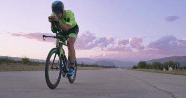 Profesyonel bir yarış bisikletine binen triatlon sporcusunun gece bisikleti eğitimi. Akşamları virajlı bir yolda sağlıklı ve yoğun bir egzersiz. Yavaş çekim izleme çekimi. 