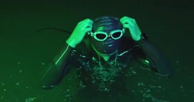 Triatlon sporcusunun portresi geceleri yoğun antrenman sırasında mola veriyor. Yüksek kaliteli görüntüler. Yavaş çekim.