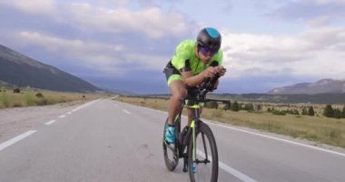 Virajlı bir kır yolunda profesyonel bir yarış bisikletine binen triatlon atleti. Yavaş çekim izleme çekimi. 