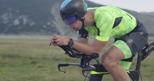 激しい田舎道での激しいワークアウトでプロのレース自転車に乗っているトライアスロン選手の閉鎖 スローモーショントラッキングショット — ストック動画