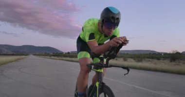 Profesyonel bir yarış bisikletine binen triatlon sporcusunun gece bisikleti eğitimi. Akşamları virajlı bir yolda sağlıklı ve yoğun bir egzersiz. Yavaş çekim izleme çekimi. 
