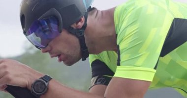 Virajlı bir kır yolunda, profesyonel bir yarış bisikletine binen triatlon sporcusuna yakın çekim. Yavaş çekim izleme çekimi. 