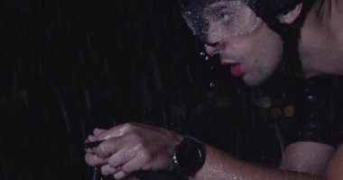 Triatlon atleti, yağmurlu bir karanlıkta yoğun bir idmanda profesyonel bir yarış bisikletine biniyor. Yağmurlu bir gecede kötü hava koşullarında antrenman ya da yarışma. Ağır çekim. Merhaba kaliteli 4K görüntüler