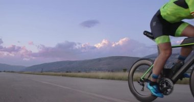 Profesyonel bir yarış bisikletine binen triatlon sporcusunun gece bisikleti eğitimi. Akşamları virajlı bir yolda sağlıklı ve yoğun bir egzersiz. Yavaş çekim izleme çekimi. 