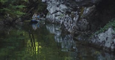 Kano yavaş çekimde kürek çekiyor. Kanocu kadın ve erkek arkadaşlarıyla güzel bir arazide kayak yapıyor. Kayakçılar gölde bir kanoyla spor yapıyorlar. Yaz boyunca su sporları. Yüksek kalite 4k görüntü