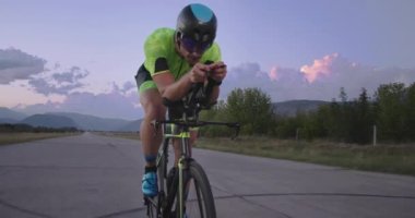 Profesyonel bir yarış bisikletine binen triatlon sporcusunun gece bisikleti eğitimi. Akşamları virajlı bir yolda sağlıklı ve yoğun bir egzersiz. Yavaş çekim izleme çekimi. 