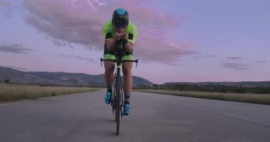 Profesyonel bir yarış bisikletine binen triatlon sporcusunun gece bisikleti eğitimi. Akşamları virajlı bir yolda sağlıklı ve yoğun bir egzersiz. Yavaş çekim izleme çekimi. 