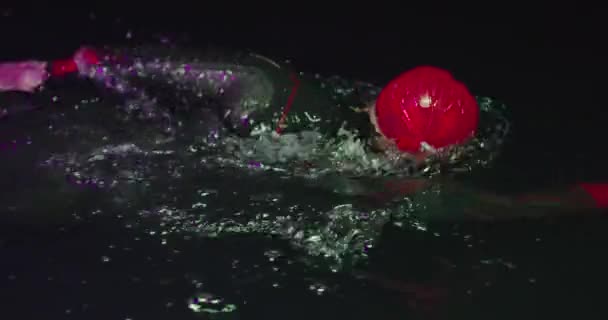 Спортсмен тріатлону, який плаває в темну ніч в гідрокостюмі — стокове відео