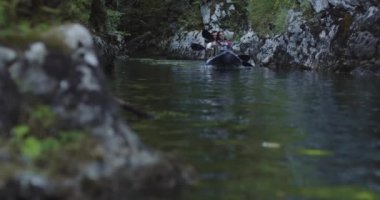 Kano yavaş çekimde kürek çekiyor. Kanocu kadın ve erkek güzel bir manzarada kayak yapıyorlar. Kayakçılar arkadaşlarıyla gölde bir kanoyla spor yapıyorlar. Yaz boyunca su sporları.