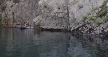 Kano yavaş çekimde kürek çekiyor. Kanocu kadın ve erkek güzel bir manzarada kayak yapıyorlar. Kayakçılar arkadaşlarıyla gölde bir kanoyla spor yapıyorlar. Yaz boyunca su sporları.