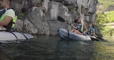 Kano yavaş çekimde kürek çekiyor. Kanocu kadın ve erkek arkadaşlarıyla güzel bir arazide kayak yapıyor. Kayakçılar gölde bir kanoyla spor yapıyorlar. Yaz boyunca su sporları. Yüksek kalite 4k görüntü