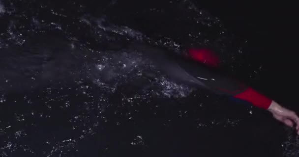 トライアスロン選手がウェットスーツを着て暗闇の中で泳ぐ — ストック動画