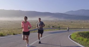 Spor yapan bir çiftin sabah dışarıda koşarkenki yavaş çekim görüntüleri, doğa tecrübeleri. Sağlıklı yaşam tarzı kavramı. Yüksek kaliteli görüntüler. Seçici odak. 