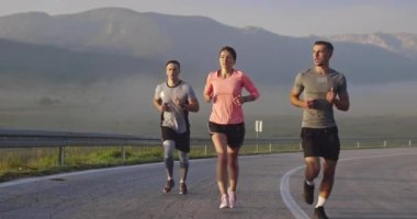 Panoramik bir kırsal yolda birlikte koşan çok ırklı bir grup sporcu. Çeşitli koşu takımları sabah antrenmanında. Yüksek kaliteli görüntüler. Ağır çekim takip ediliyor.. 