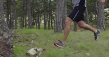 Erkek sporcu ormanda koşuyor. Hareketli bir genç adam yoğun bir koşu egzersizi yapıyor..