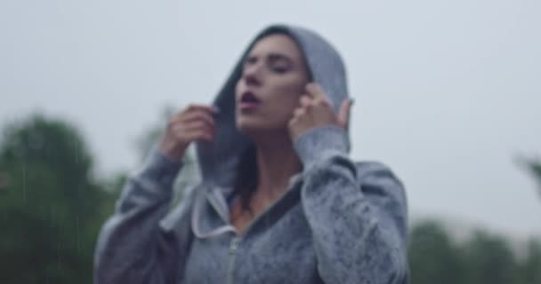 ผู้หญิงสาวถอดฮู้ดออกพักผ่อนหลังจากวิ่งในวันที่ฝนตก . — วีดีโอสต็อก