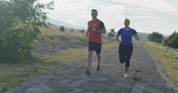 Követés lassított felvétel sportos pár kocogás szabadban reggel, nyomvonal futás tapasztalat a természetben. Egészséges életmód koncepció. — Stock videók