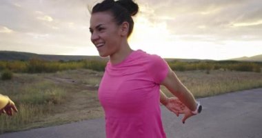 İki çok ırklı kız sokakta birlikte koşuya çıkmadan önce bacaklarını esnetiyorlar..