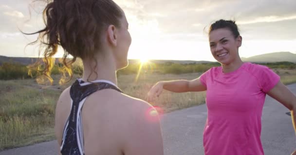 Twee multi-etnische meisjes die zich samen uitstrekken in de straat, hun benen strekken voor een run. — Stockvideo