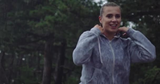 Uma jovem tira o capuz descansando depois de correr em um dia chuvoso. — Vídeo de Stock