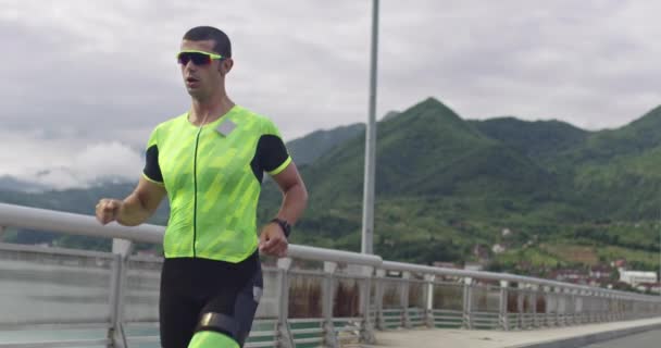 Triatlón: triatleta masculino que corre en el entrenamiento del traje de triatlón para la carrera de Ironman. Hombre corredor ejercitando jogging en la mañana. — Vídeos de Stock