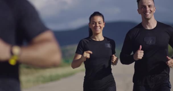 Panoramik bir kırsal yolda birlikte koşan çok ırklı bir grup sporcu. Sabah antrenmanına çıkan çeşitli koşucular.. — Stok video
